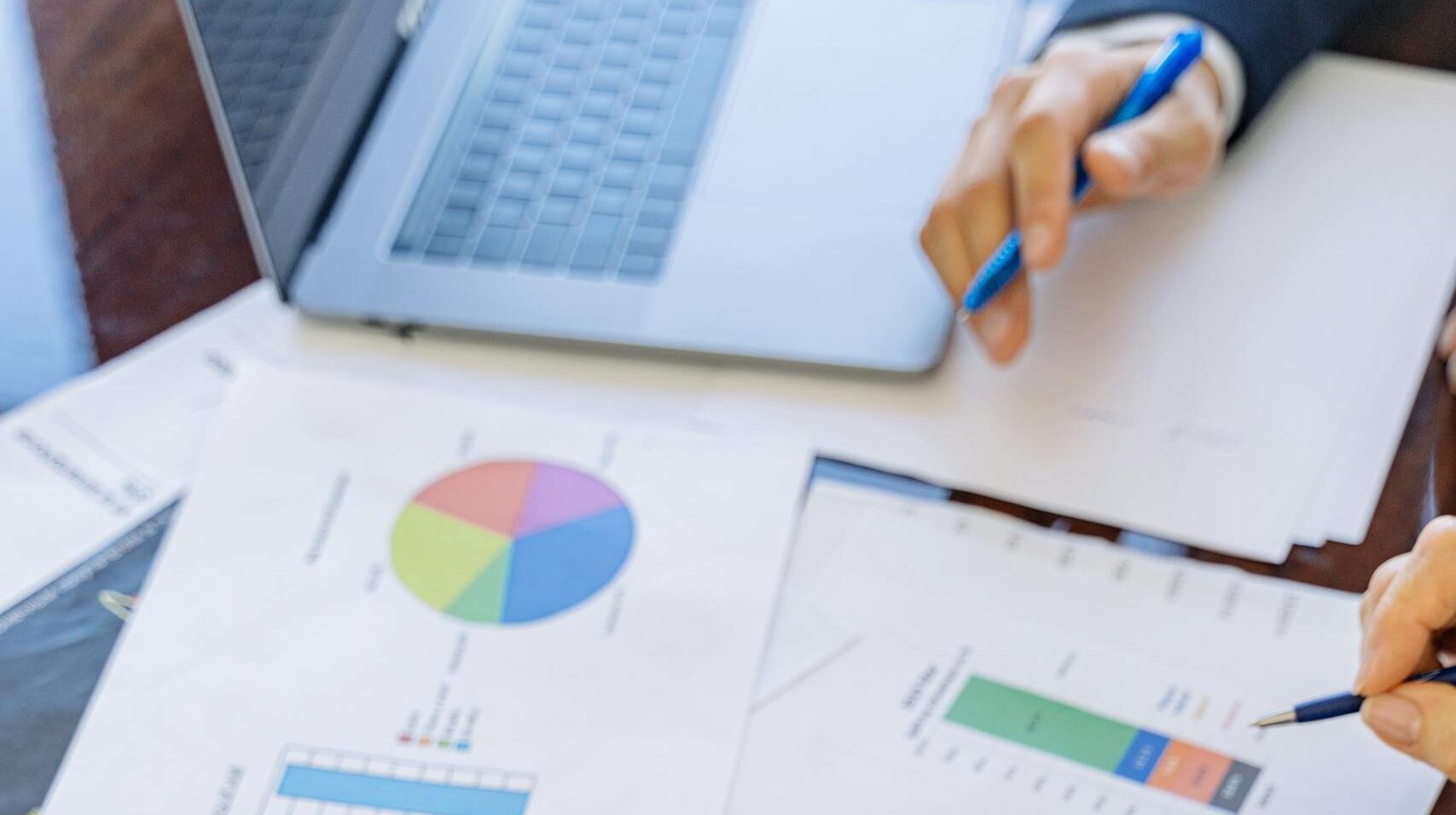 A close-up of businesspeople analyzing financial data and charts during a meeting.
